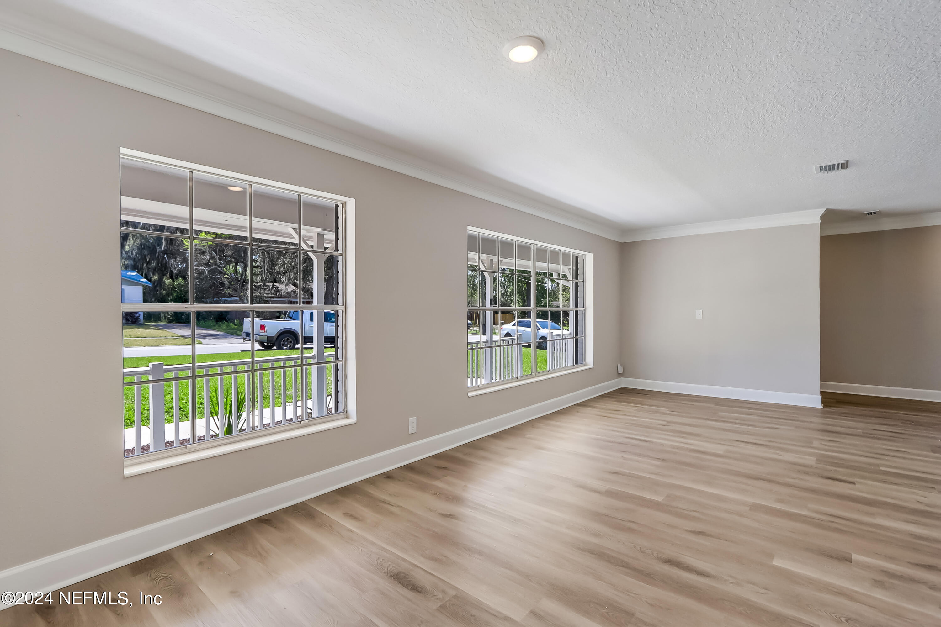 327 Neptune Road Orange Park, FL 32073 - Photo 6 of 40 a view of an empty room with wooden floor and a window
