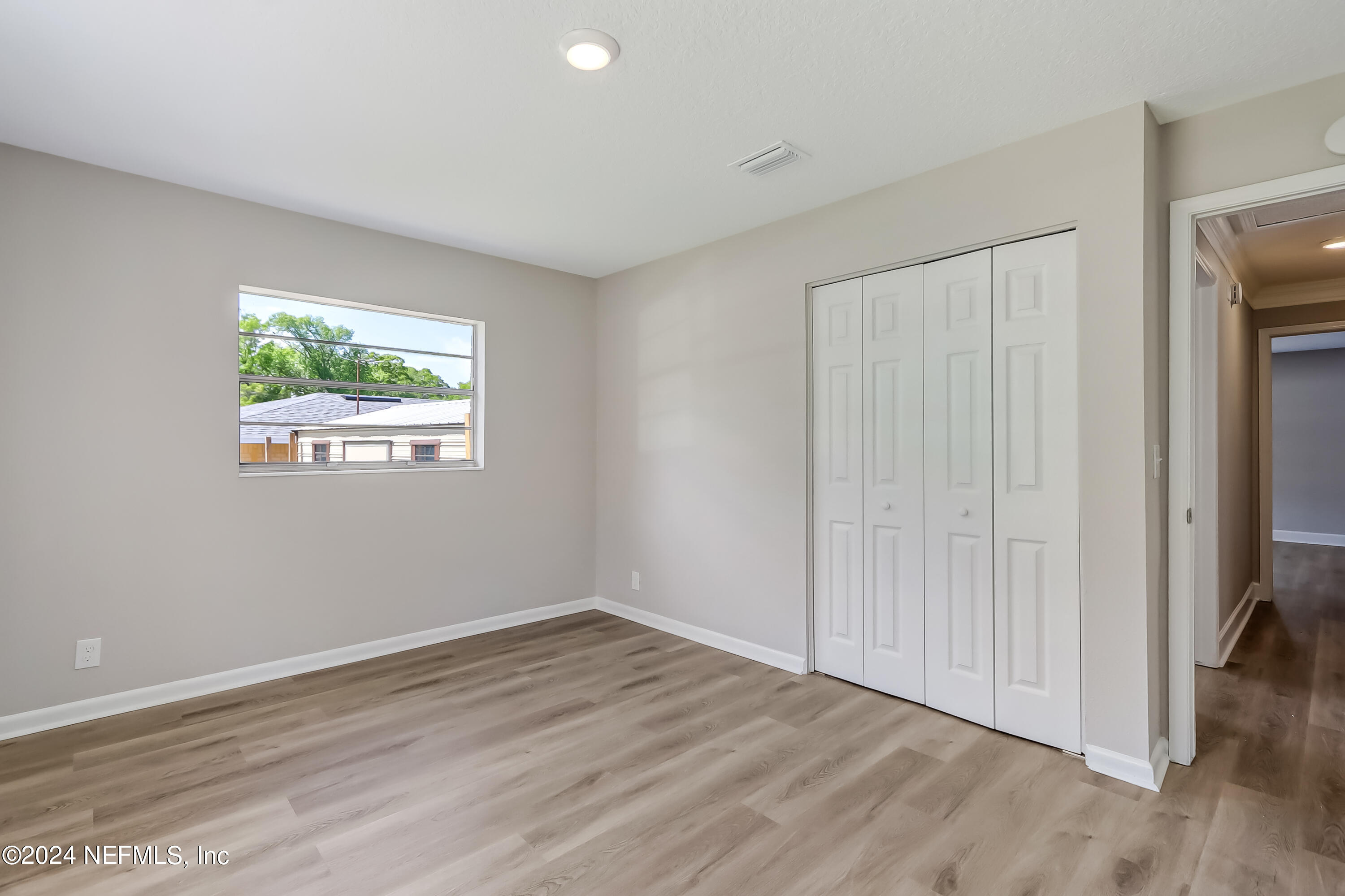 327 Neptune Road Orange Park, FL 32073 - Photo 8 of 40 an empty room with wooden floor closet and windows