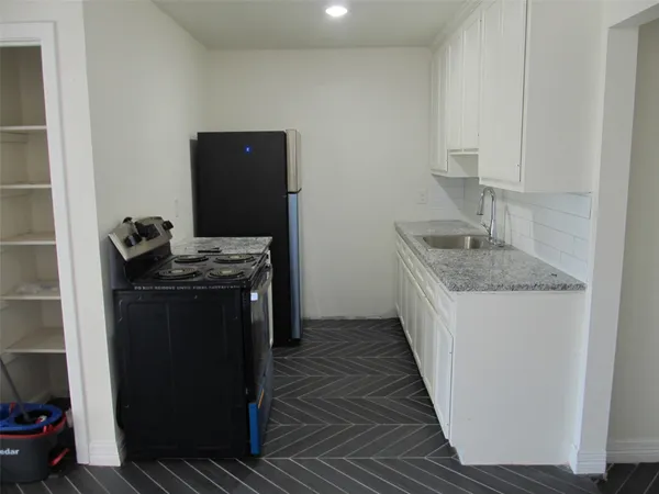 a kitchen with granite countertop a sink stove and cabinets