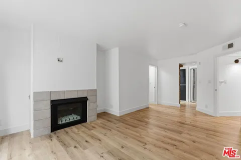 a view of an empty room with wooden floor fireplace and a window