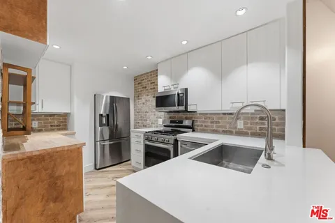a kitchen with stainless steel appliances kitchen island granite countertop a refrigerator a stove and a sink