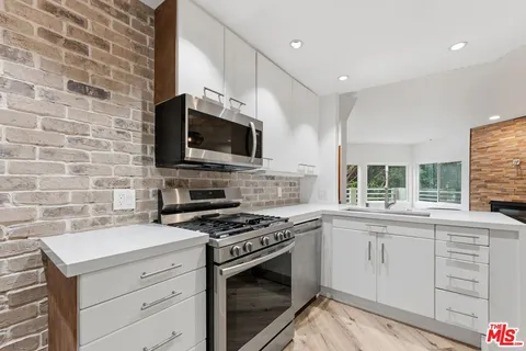 a kitchen with cabinets stainless steel appliances and wooden floor