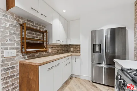 a kitchen with stainless steel appliances a refrigerator a stove and white cabinets