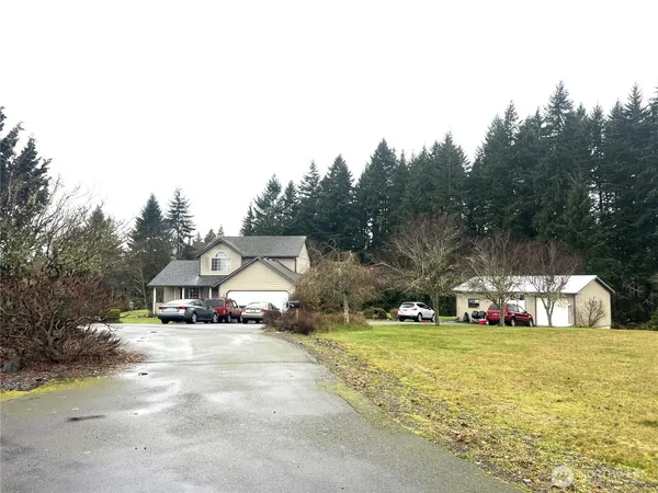 a view of front of house with outdoor space and trees in the background