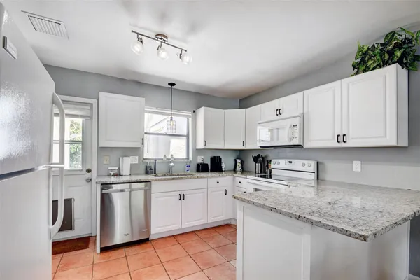 a kitchen with white cabinets sink and appliances