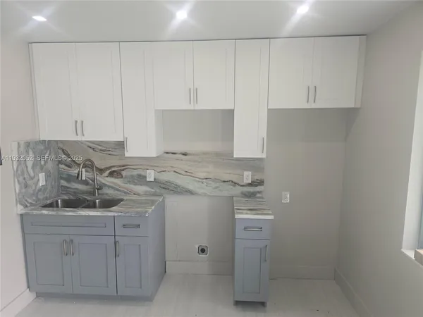 a kitchen with white cabinets and sink