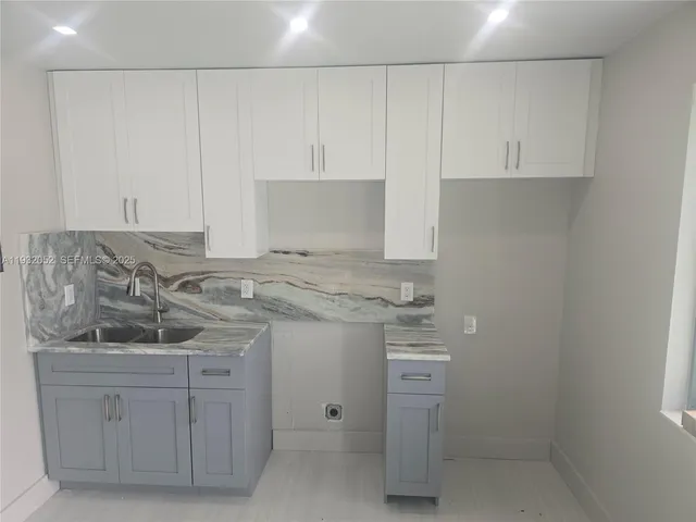 a kitchen with white cabinets and sink