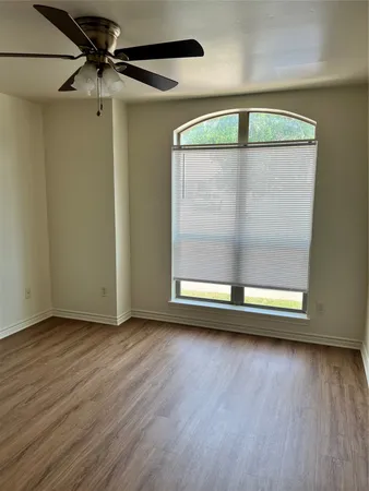 an empty room with wooden floor fan and windows