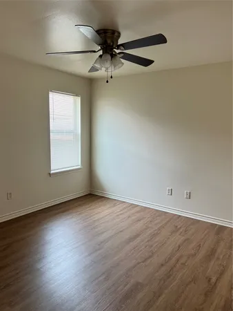 an empty room with wooden floor fan and windows