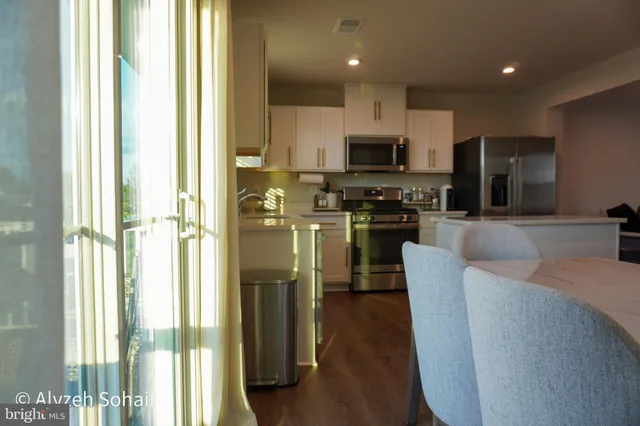 a kitchen with stainless steel appliances granite countertop a refrigerator a sink a stove and oven with wooden floor