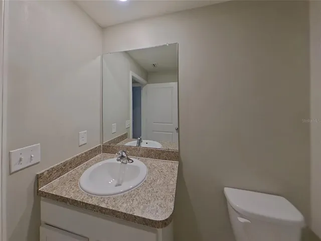 a bathroom with a granite countertop toilet sink and mirror