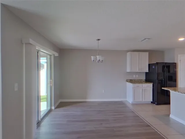 a view of kitchen with granite countertop cabinets and refrigerator
