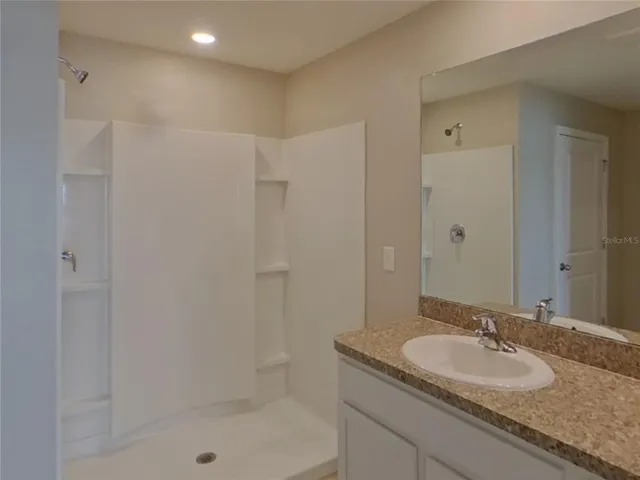 a bathroom with a granite countertop sink a mirror and a shower