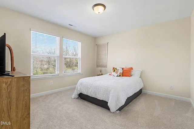 a bed sitting in a spacious bedroom next to a window
