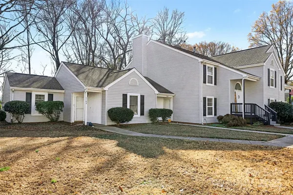 a view of a white house next to a yard with big trees