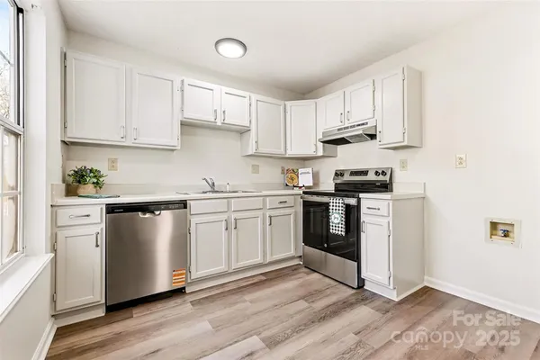 a kitchen with stainless steel appliances white cabinets and wooden floor