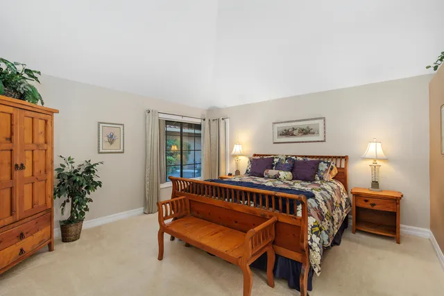 a bed sitting in a bedroom next to a window and potted plant