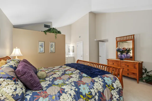a bedroom with a bed and a lamp on dresser