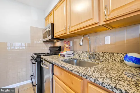 a kitchen with stainless steel appliances granite countertop a sink a stove and cabinets