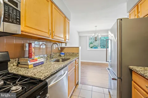 a kitchen with granite countertop stainless steel appliances a sink and refrigerator