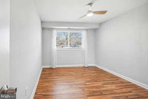 an empty room with wooden floor cabinet and windows