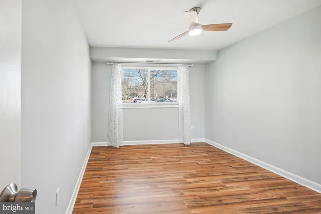 an empty room with wooden floor cabinet and windows