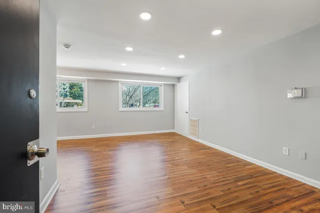 an empty room with wooden floor and windows