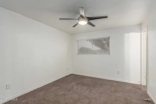 an empty room with a ceiling fan and a window