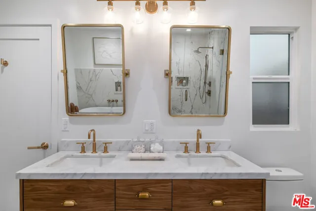 a bathroom with double vanity sinks granite vanity and a mirror