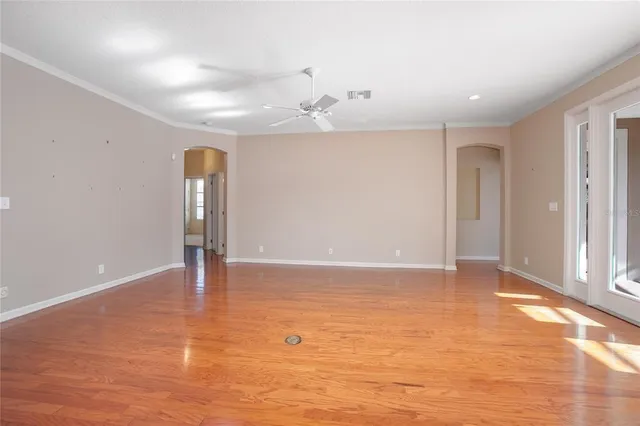 a view of an empty room with window and wooden floor