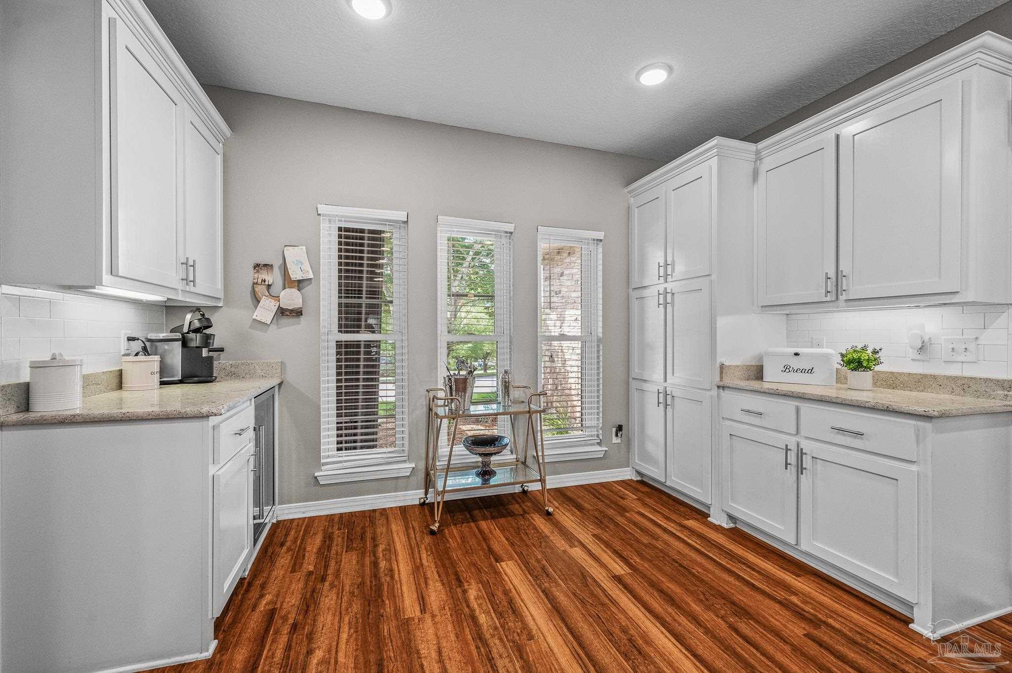 10443 Tam O Shanter Road Pensacola, FL 32514 - Photo 20 of 57 a kitchen with wooden floors and white cabinets