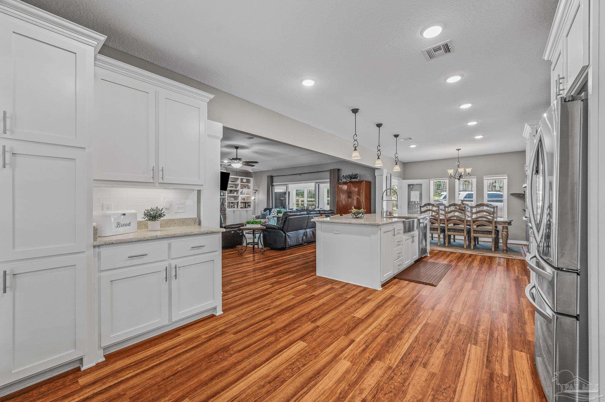 10443 Tam O Shanter Road Pensacola, FL 32514 - Photo 22 of 57 a large white kitchen with wooden floors and view living room