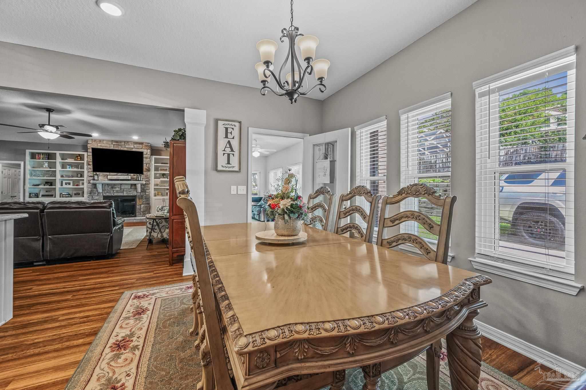 10443 Tam O Shanter Road Pensacola, FL 32514 - Photo 24 of 57 a dining room with furniture a chandelier and wooden floor