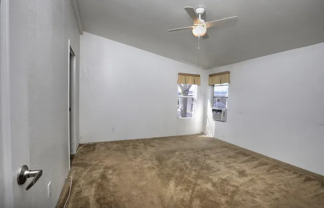 an empty room with windows and fan