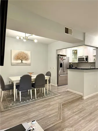 a kitchen with stainless steel appliances granite countertop a stove top oven a sink a dining table and chairs with wooden floor