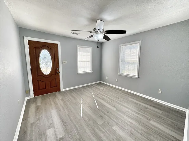 a view of an empty room with a window and wooden floor