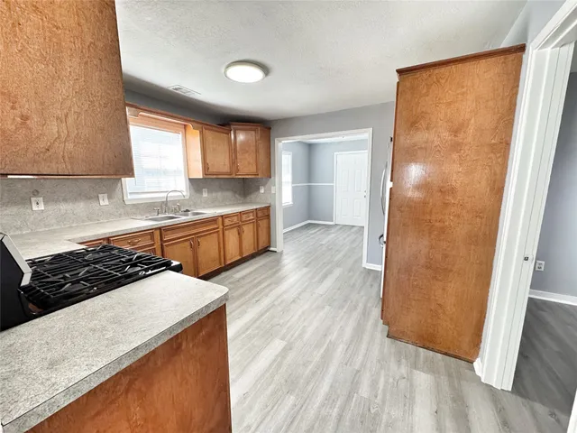a kitchen with a sink a stove a refrigerator and wooden floor