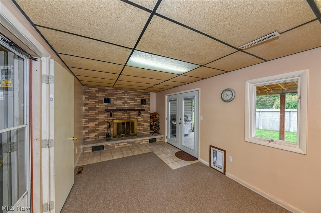 1275 Sandy Lake Road Ravenna, OH 44266 - Photo 16 of 34 Family room with wood-burning fireplace, exit to the covered patio, and to the garage. This carpet is brand new!