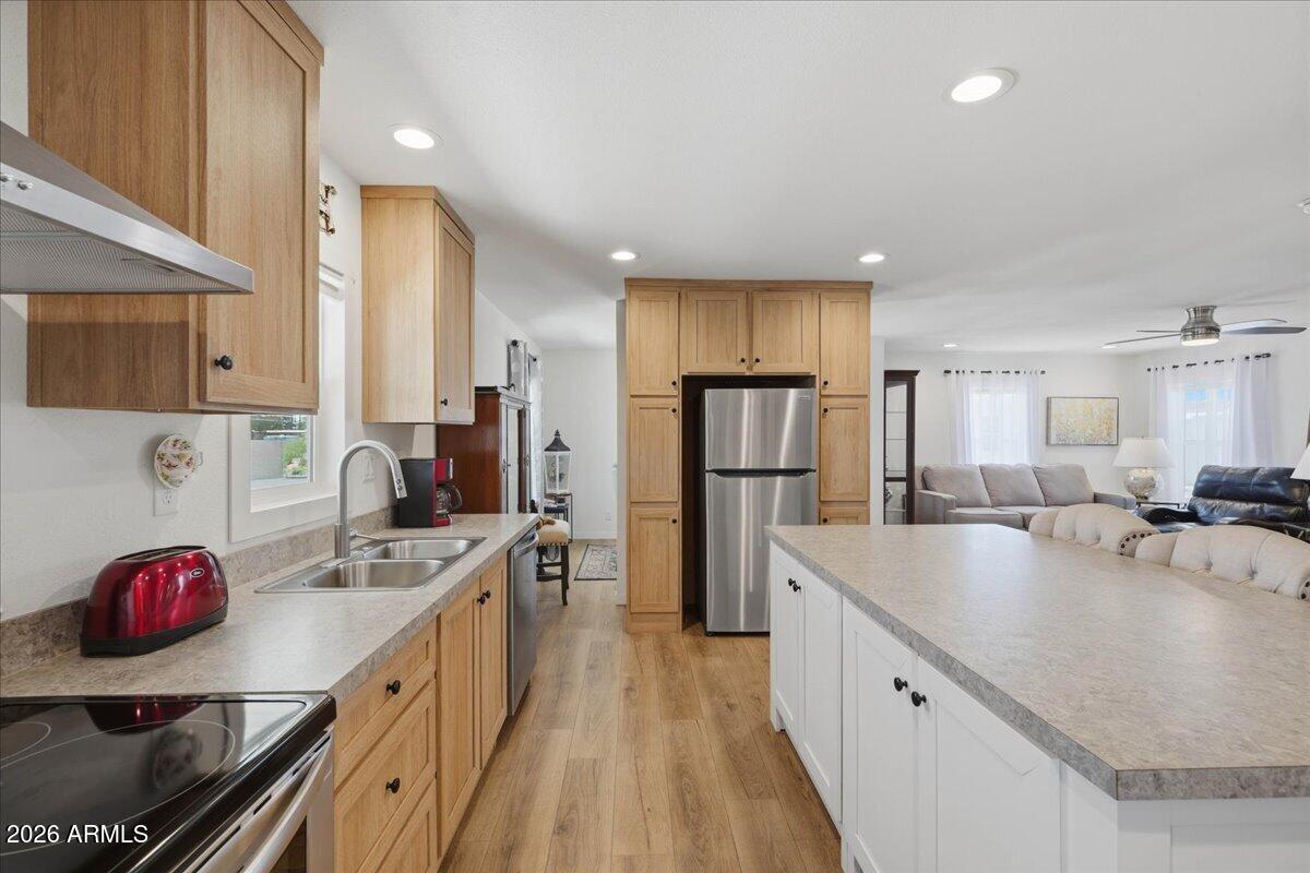 320 East McKellips Road, Unit 199 Mesa, AZ 85201 - Photo 13 of 32 a large kitchen with stainless steel appliances a sink dishwasher a refrigerator and cabinets with wooden floor
