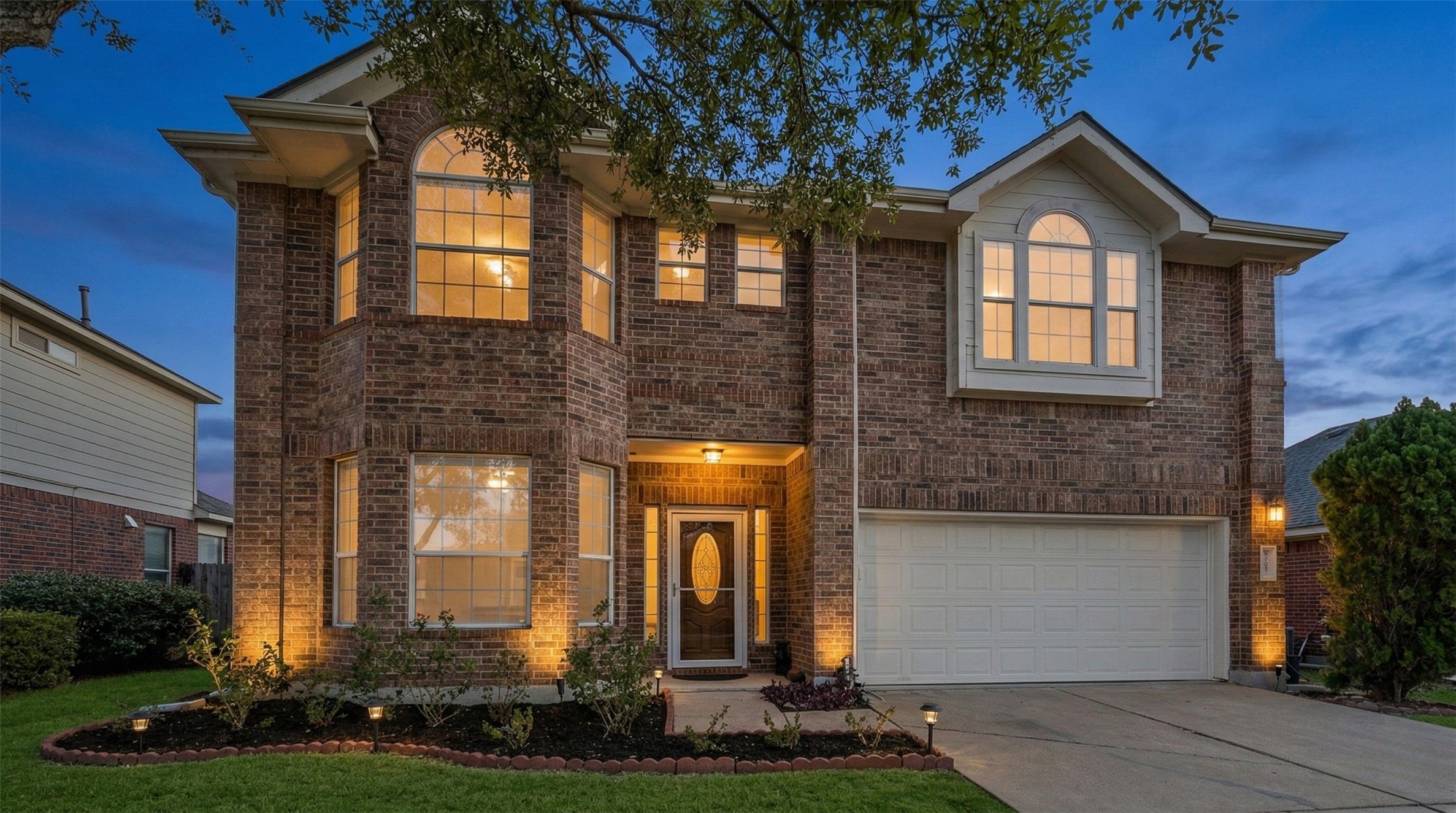 Traditional-style house with an attached garage, brick siding, and concrete driveway