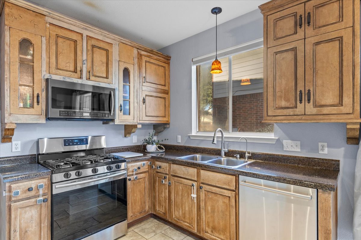3523 Cheyenne Street Round Rock, TX 78665 - Photo 11 of 34 Kitchen featuring stainless steel appliances, dark countertops, wood finish cabinetry, and pendant lighting