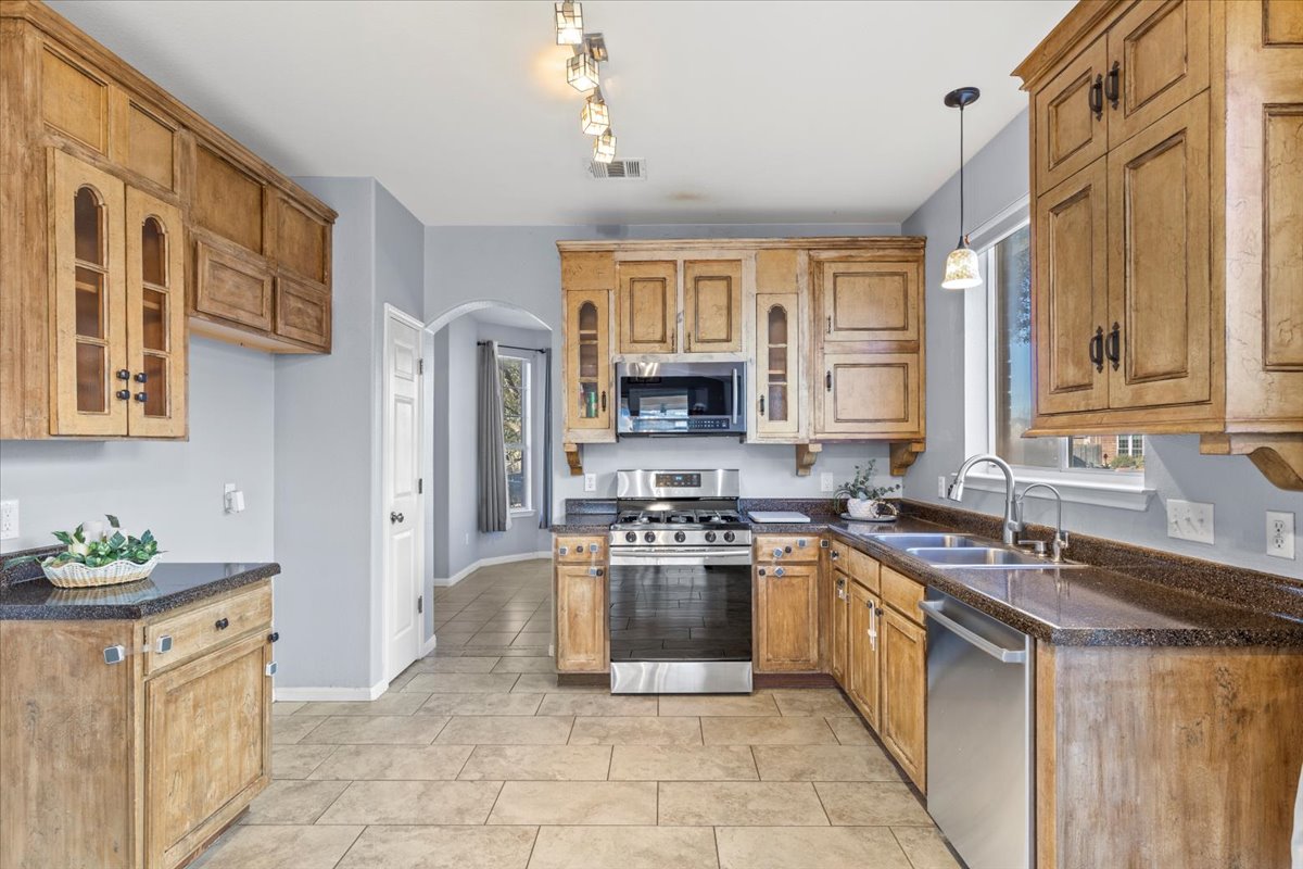 3523 Cheyenne Street Round Rock, TX 78665 - Photo 11 of 34 Kitchen featuring glass insert cabinets, stainless steel appliances, arched walkways, and wood finish cabinetry