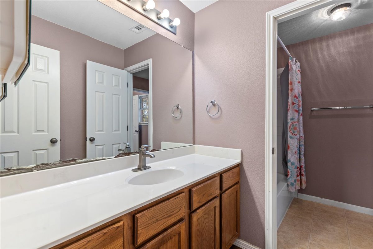 3523 Cheyenne Street Round Rock, TX 78665 - Photo 21 of 34 Bathroom with shower / tub combo with curtain, vanity, a textured wall, and light tile patterned floors