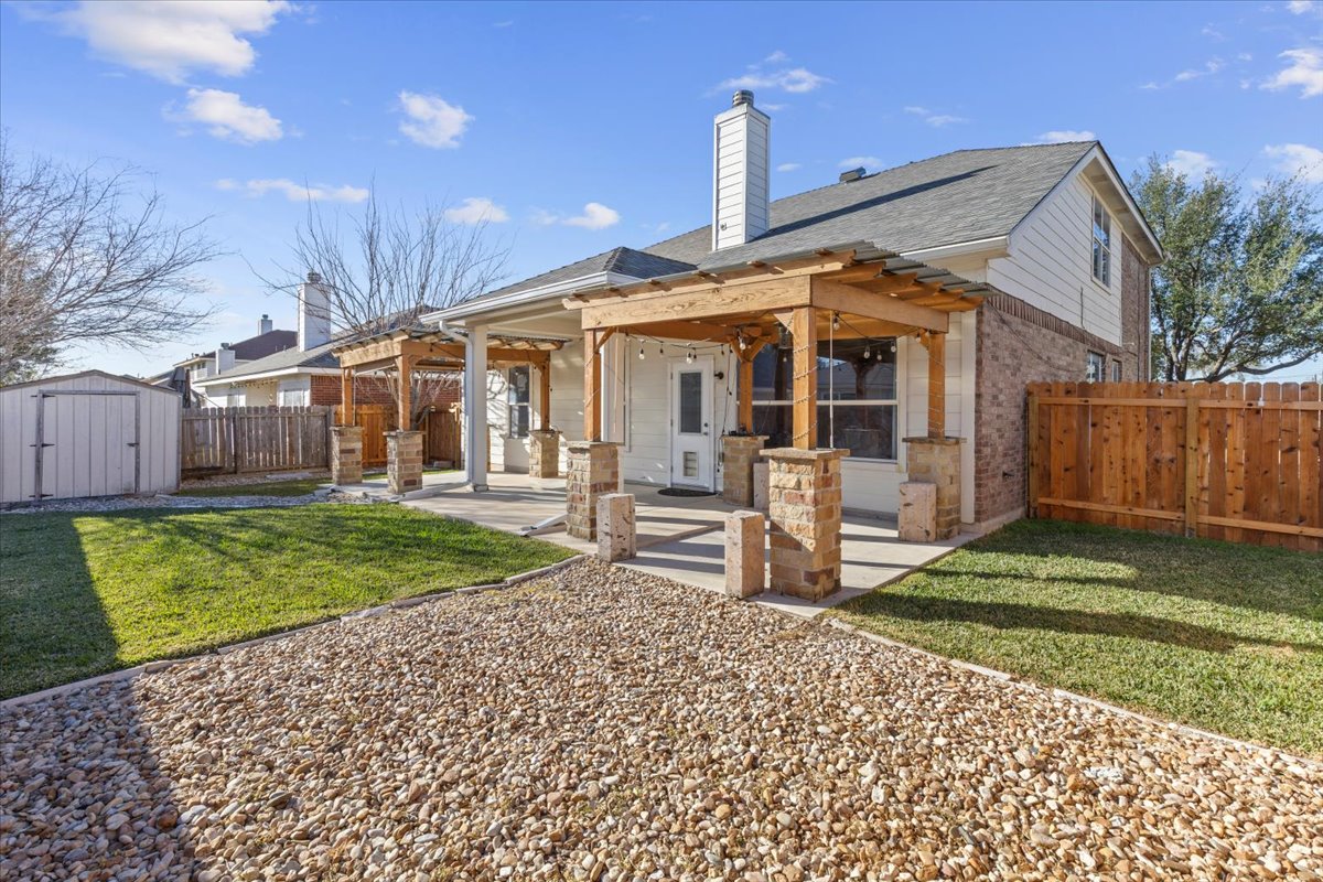 3523 Cheyenne Street Round Rock, TX 78665 - Photo 29 of 34 Rear view of property with a patio, a storage unit, brick siding, a fenced backyard, and a chimney