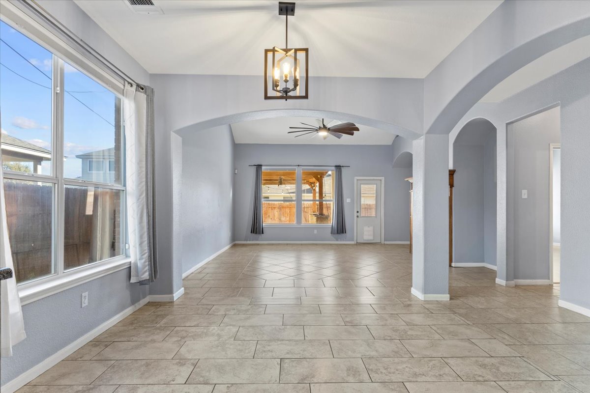 3523 Cheyenne Street Round Rock, TX 78665 - Photo 6 of 34 Empty room with hanging lights, arched walkways, a ceiling fan, and light tile patterned floors