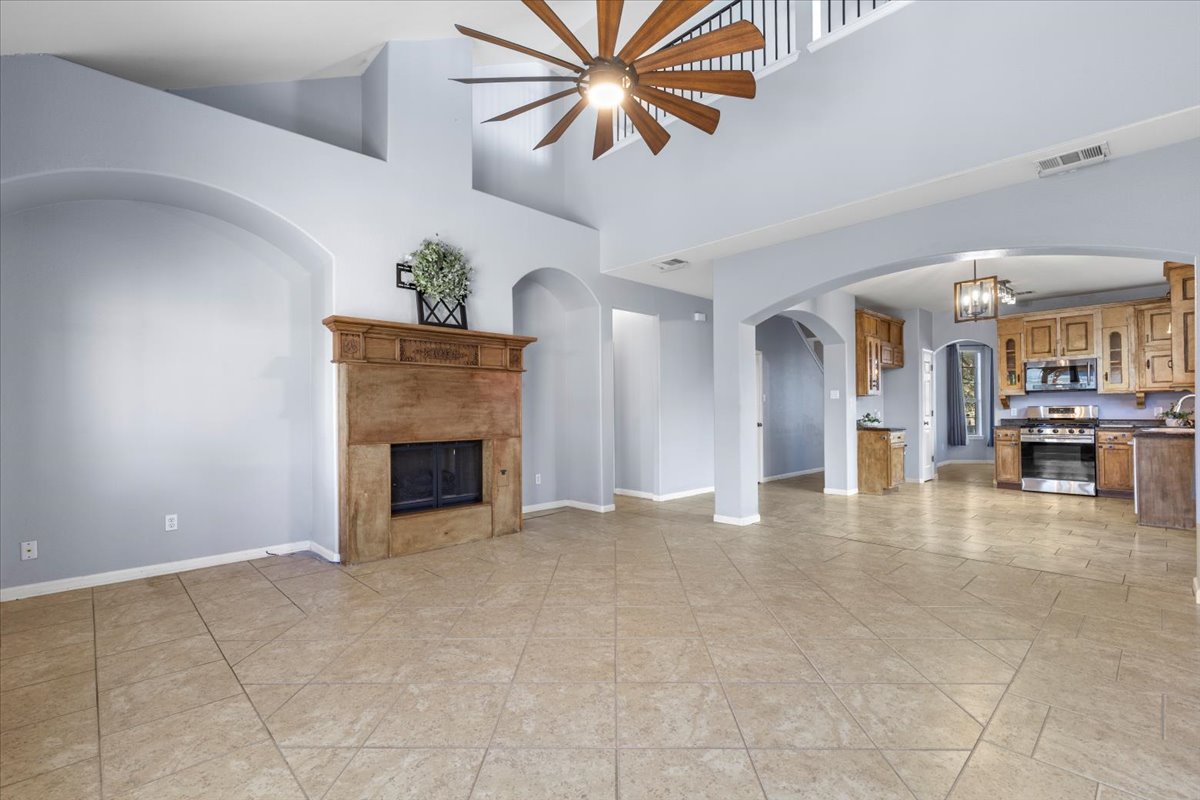 3523 Cheyenne Street Round Rock, TX 78665 - Photo 8 of 34 Unfurnished living room with a fireplace, lofted ceiling, and a ceiling fan