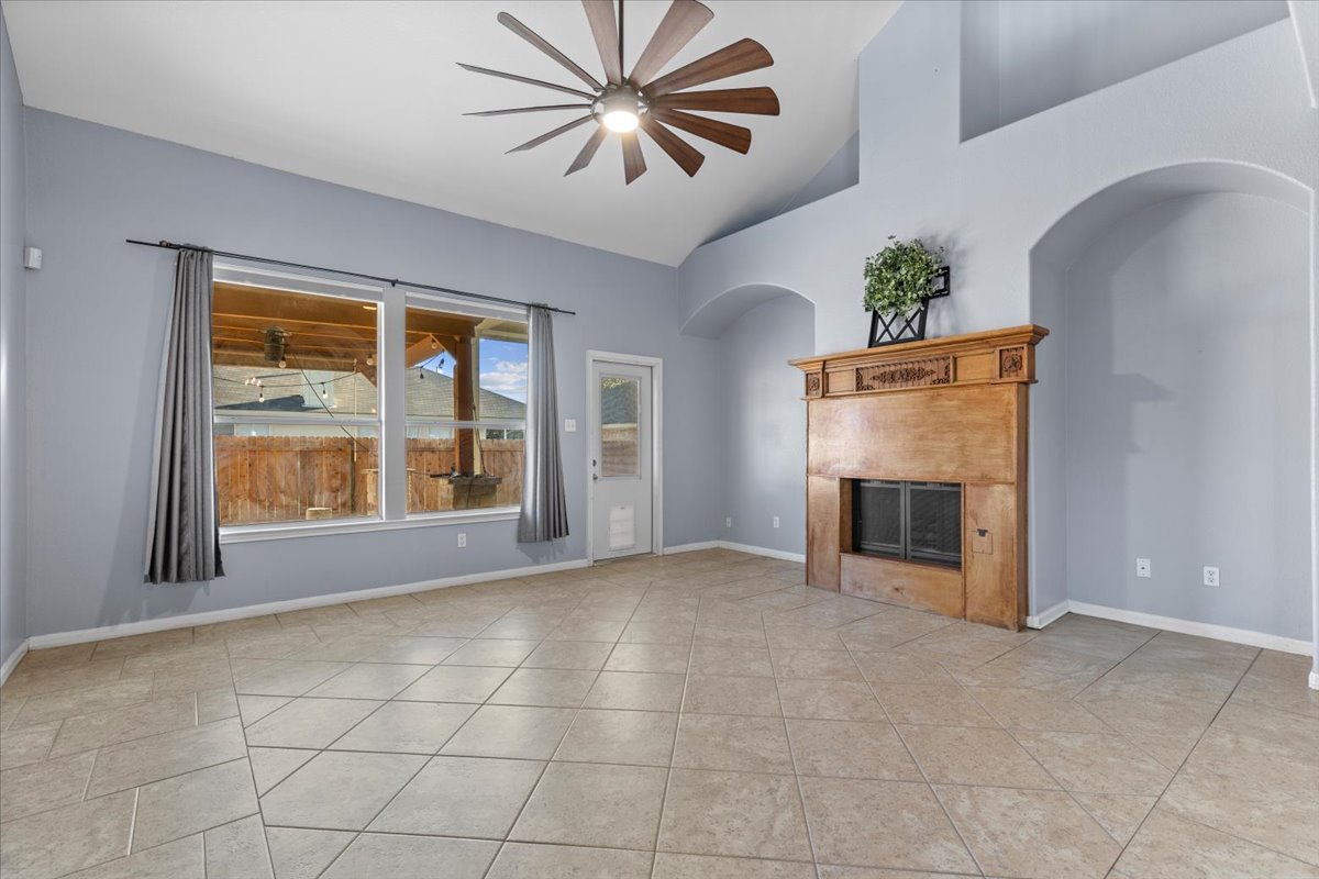 3523 Cheyenne Street Round Rock, TX 78665 - Photo 8 of 34 Unfurnished living room featuring a fireplace, vaulted ceiling, ceiling fan, and light tile patterned floors