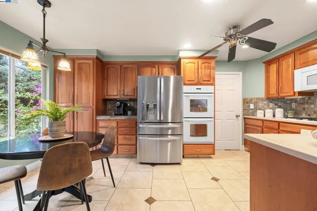 a kitchen with stainless steel appliances a stove a refrigerator and a dining table