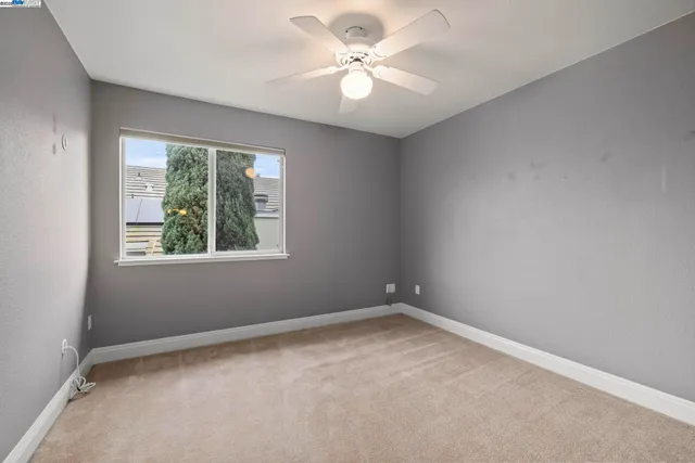 an empty room with a window and a fan