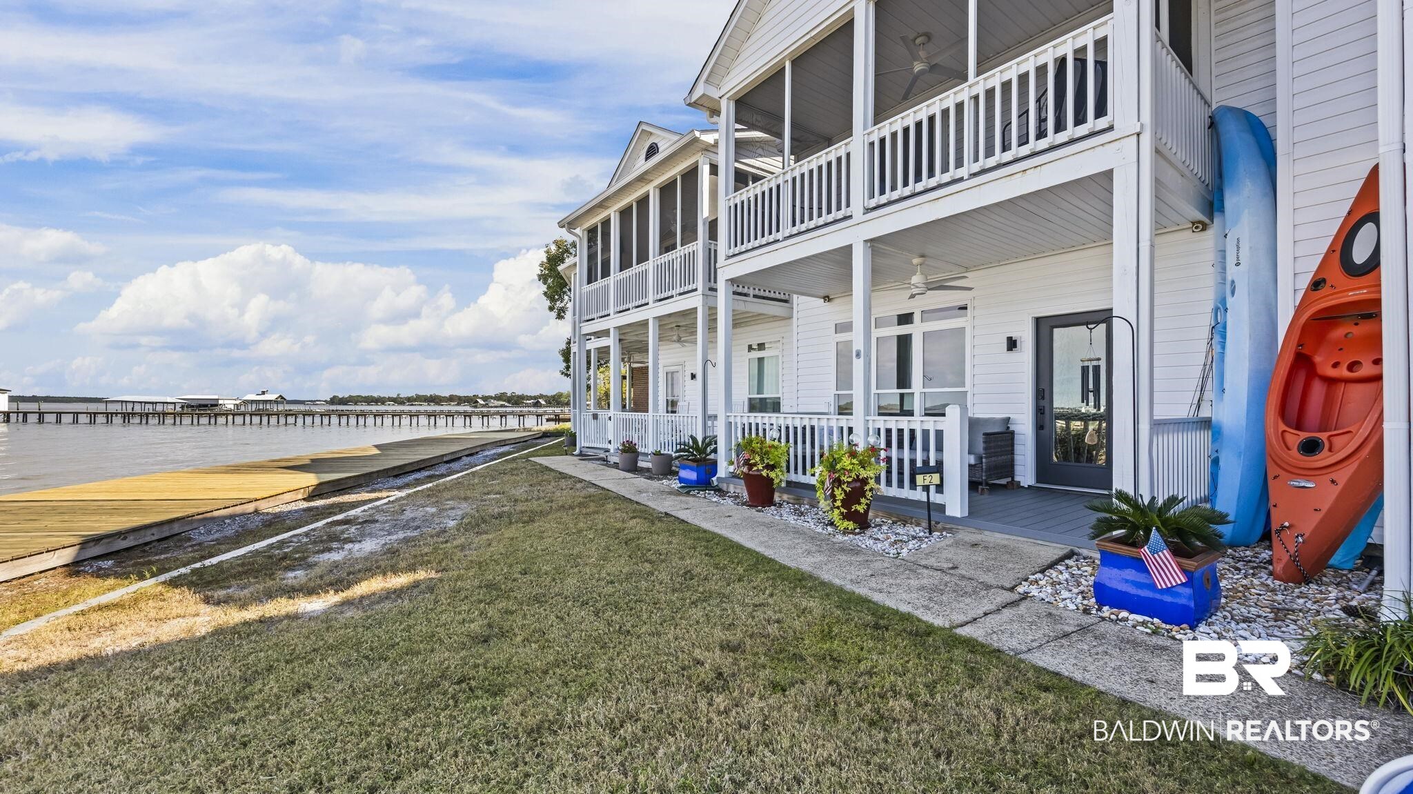 26063 Canal Road, Unit 2F Orange Beach, AL 36561 - Photo 5 of 36 View of green lawn featuring a deck with water view and ceiling fan